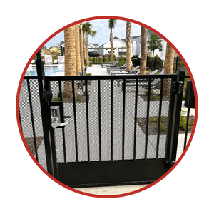 Black metal pool gate with keypad lock, leading to a pool area with lounge chairs, palm trees, and houses in the background.