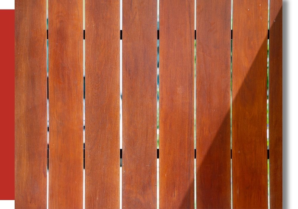 Wooden planks arranged vertically with narrow gaps between them; a diagonal shadow falls across the right side of the surface.